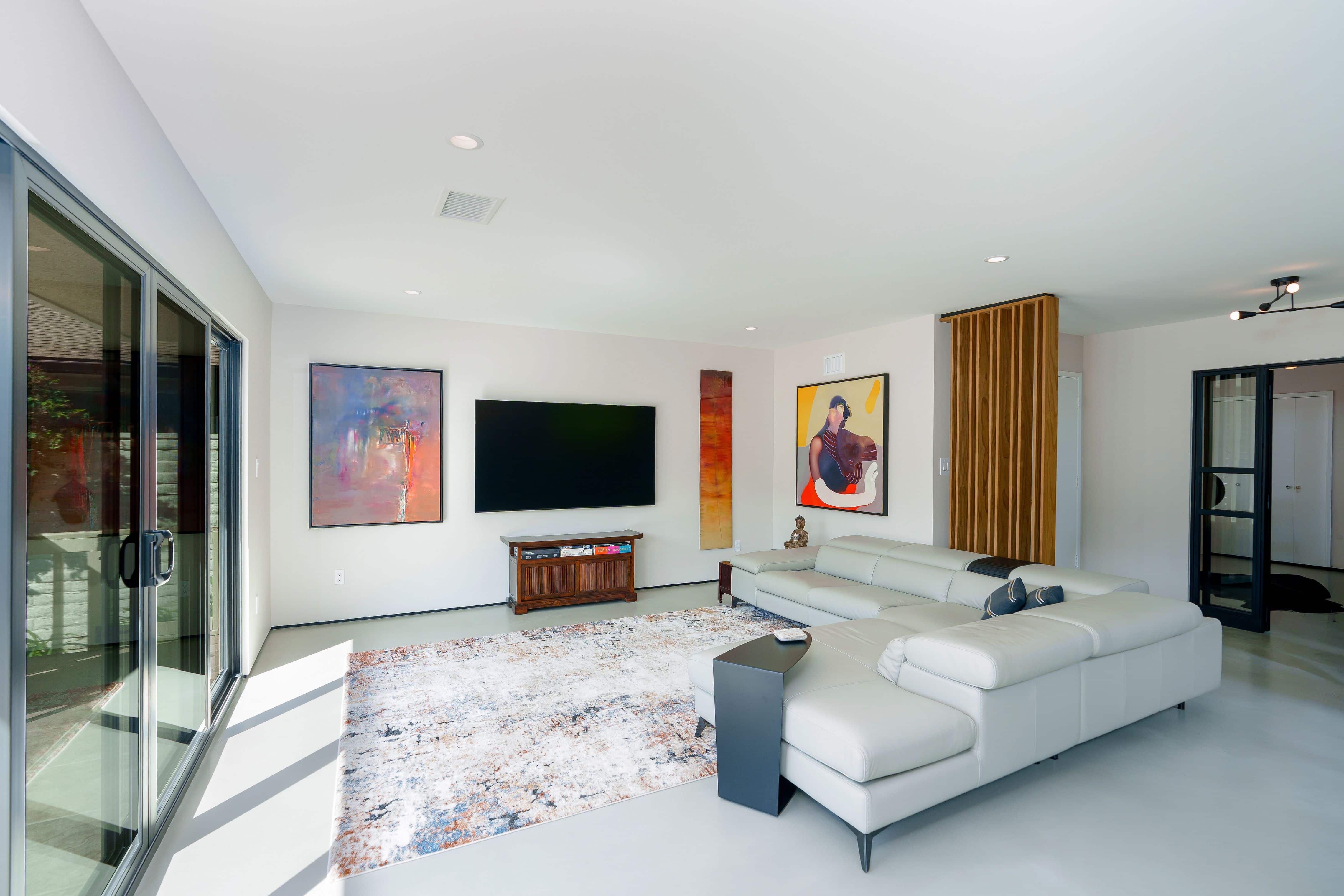 Open kitchen and living area with concrete floors and two wide black sliding doors overlooking a patio and the lake