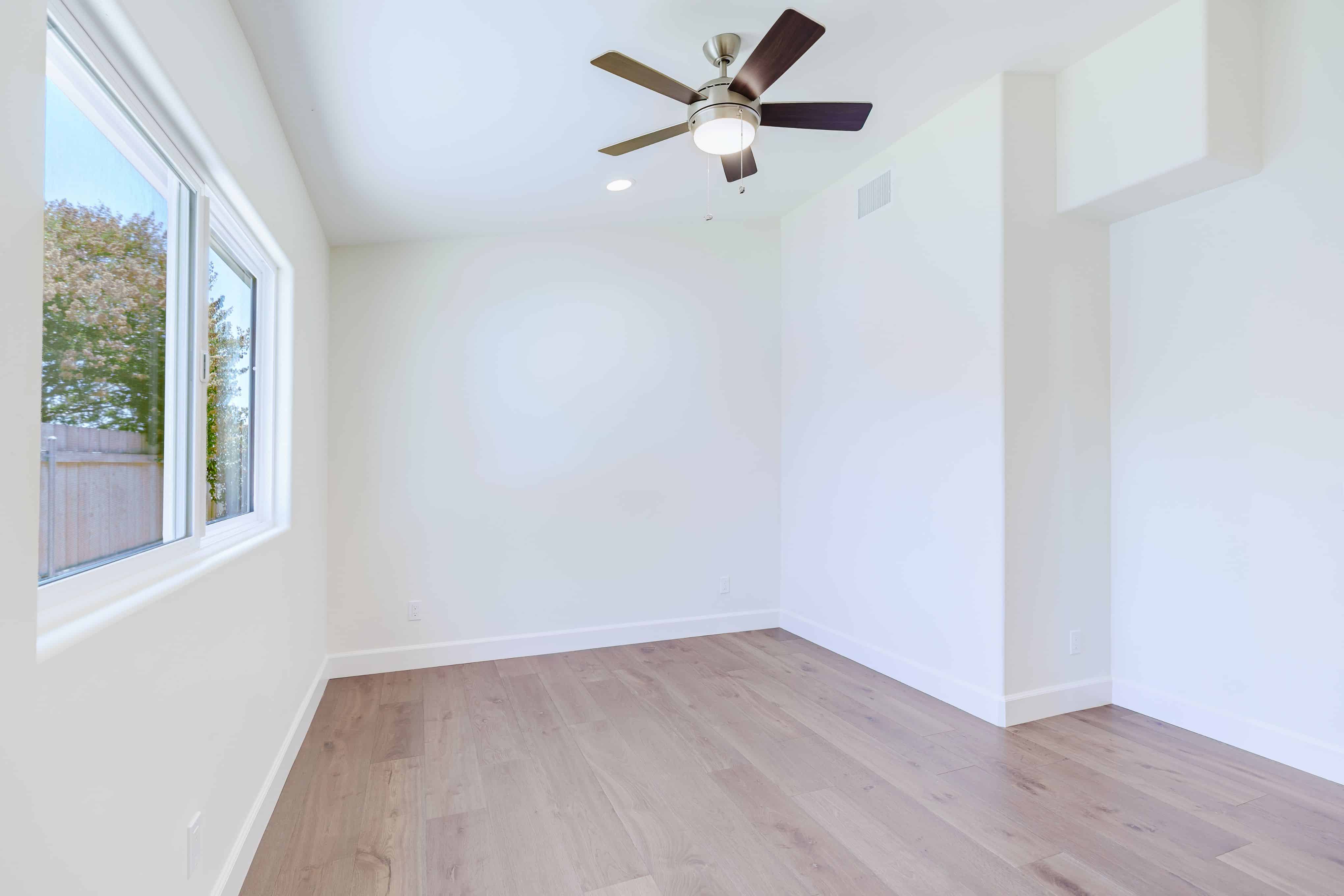 Bright bedroom with a large sliding window, ceiling fan, recessed lighting and wide-plank wood-look flooring