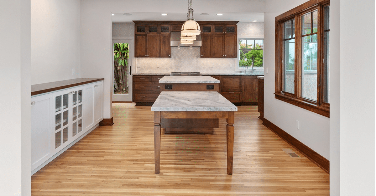 Open kitchen and dining area with warm wood cabinetry, hardwood floors, and a central worktable.