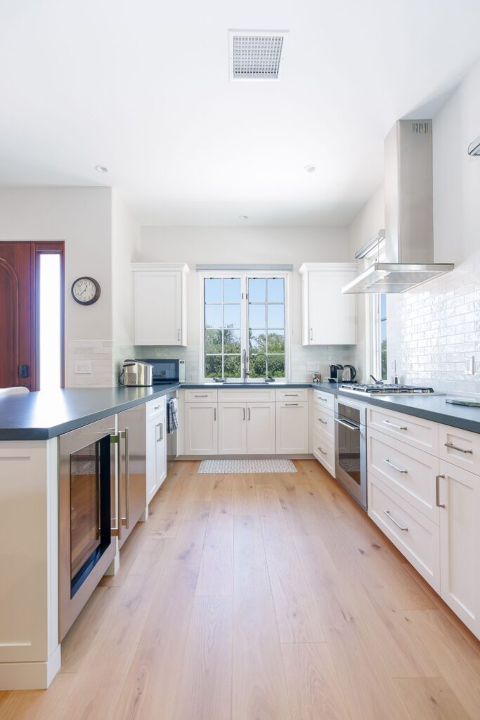 Golf turf beside a lounge area, opening to a white shaker kitchen and a wood entry door with sidelights in an ADU