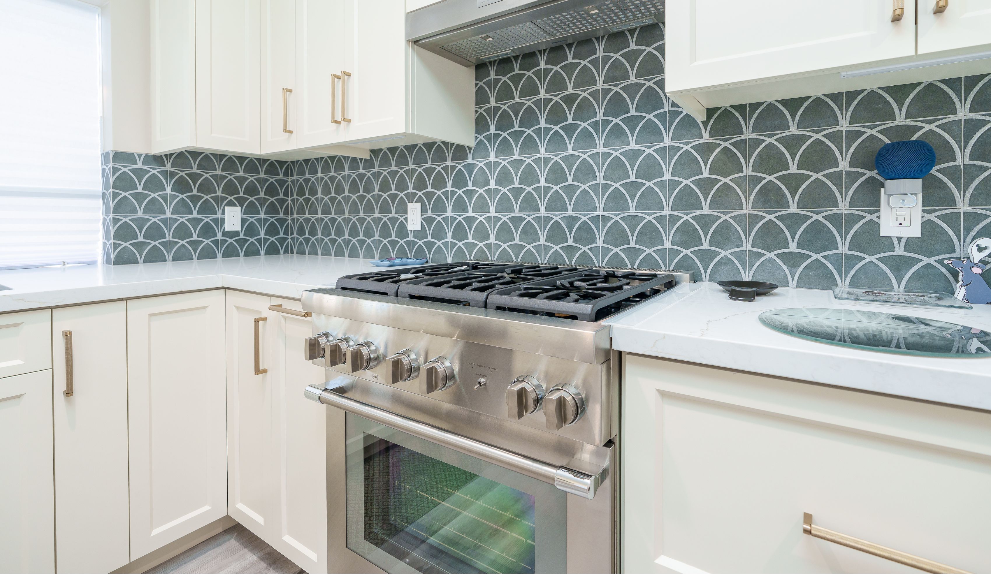 Mira Mesa kitchen remodel detail with stainless gas range, hood, gray-green fan tile backsplash and brass cabinet pulls