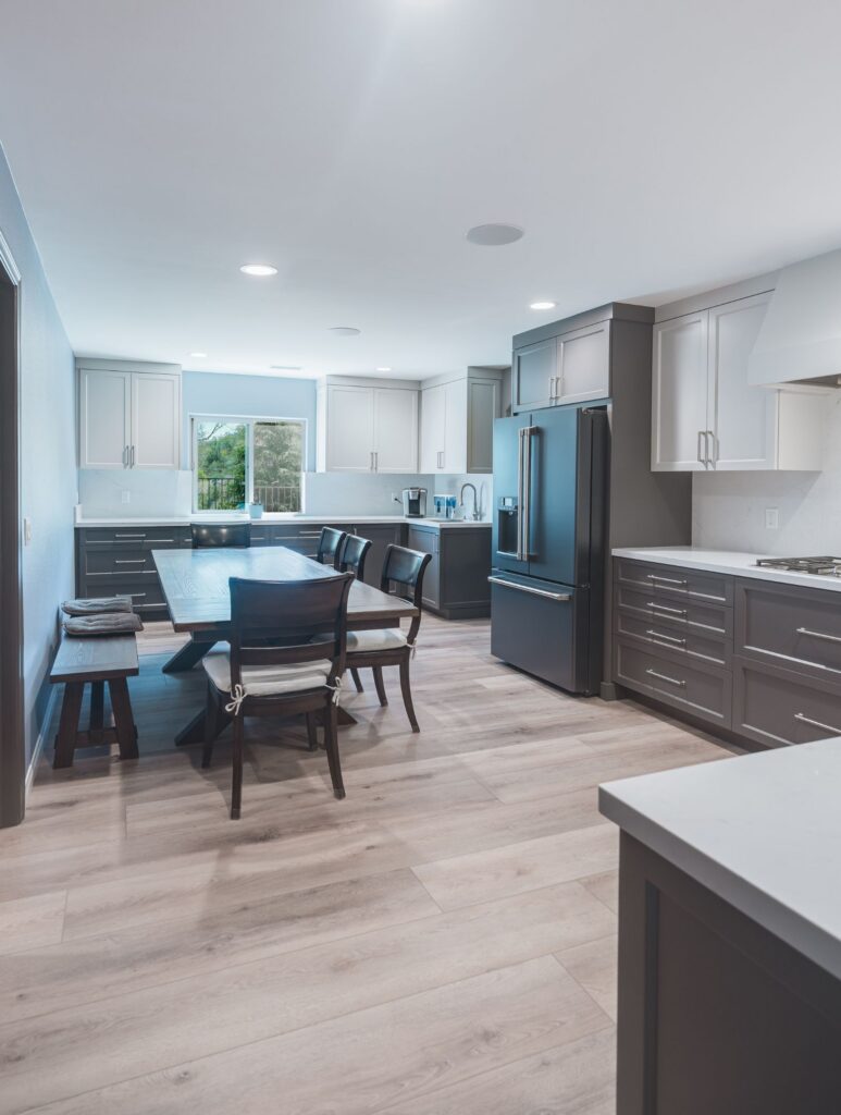 San Diego kitchen remodel with an open dining area, gray and white shaker cabinets, quartz backsplash, black refrigerator and LVP floor